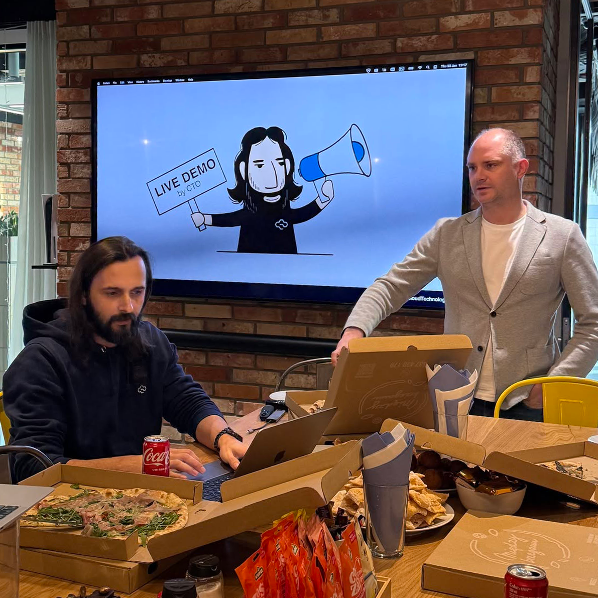 CTO giving a live demo — team watching on office TV screen
